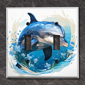 May include: A white light switch cover with a watercolor illustration of a dolphin jumping out of the water with blue and white flowers.