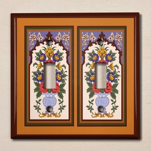 May include: A double light switch cover with a decorative design featuring a floral motif in shades of red, yellow, blue, and green. The design is framed by a brown border and a gold background.