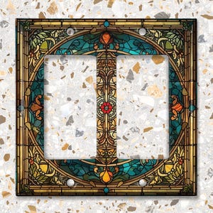 May include: Double light switch cover with a stained glass design featuring a blue, green, and gold color scheme with floral patterns.