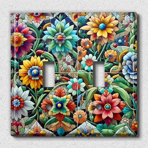 May include: A colourful floral design with a mosaic pattern on a double light switch cover. The design features a variety of flowers in shades of red, yellow, blue, green, and white.