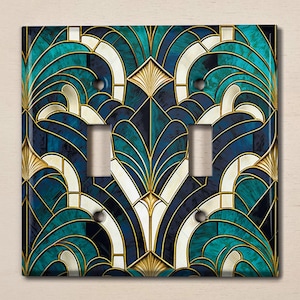 May include: A double light switch cover with an art deco design featuring teal, gold, and white geometric shapes.