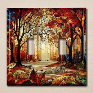 May include: A stained glass light switch cover featuring a colorful autumn forest scene with trees, leaves, and a path. The colors are vibrant and include shades of red, orange, yellow, green, and brown.