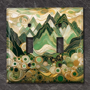 May include: A double light switch cover with a green and gold abstract mountain landscape design. The design features swirling lines, circles, and a mountain range.