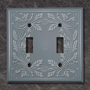 May include: A gray double light switch cover with an embossed floral design.