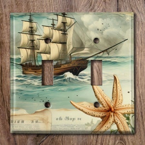 May include: A vintage-style light switch cover featuring a detailed illustration of a sailing ship with billowing sails on a blue ocean with a starfish in the foreground. The text "Oh! Ship" is visible in the lower right corner.