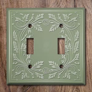 May include: A light green double light switch cover with an embossed floral design.