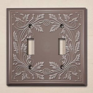 May include: A brown double light switch cover with a decorative floral design in a silver colour.