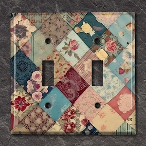 May include: A double light switch cover with a patchwork design featuring various floral patterns in shades of blue, pink, red, and green. The cover is made of ceramic and has a glossy finish.