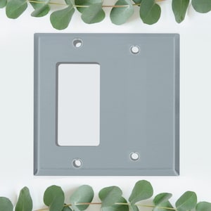 May include: A gray plastic wall plate with two rectangular openings for electrical outlets. The plate has four screw holes for mounting.