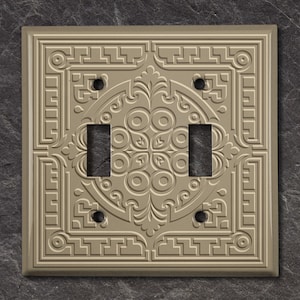 May include: A decorative light brown wall plate with an ornate design and two toggle switches.