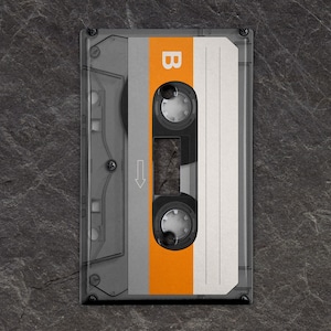 May include: A vintage audio cassette tape with a clear plastic case, a black label, and an orange stripe. The label has the letter "B" printed on it.