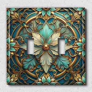 May include: A decorative light switch cover with a gold and teal floral design. The design features intricate details and a circular pattern.
