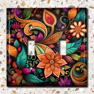 May include: A double light switch cover with a colorful floral design. The design features a variety of flowers, leaves, and swirls in shades of orange, red, purple, green, and blue on a black background.