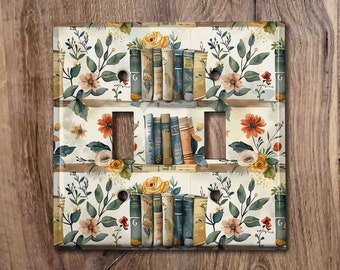 May include: A white light switch cover featuring a floral design and a bookshelf filled with books. The books are in a variety of colours and have gold lettering. The floral pattern includes yellow, orange, red, and green flowers.