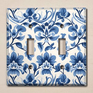 May include: A white light switch cover with a blue floral pattern. The pattern features stylised flowers and leaves.