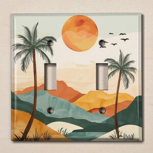 May include: A decorative light switch cover featuring a tropical landscape design. The artwork includes a large orange sun, palm trees, mountains, and birds. The color palette consists of orange, green, and blue hues.