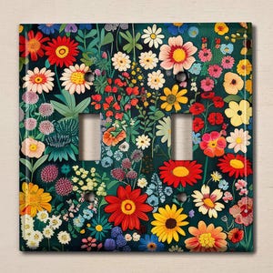 Peut inclure: Une plaque de prise de courant avec un motif floral. Le design présente une variété de fleurs colorées sur un fond vert foncé.