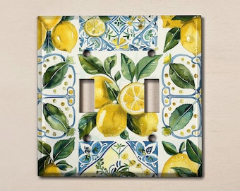May include: A light switch cover with a lemon and leaf design. The cover features a white background with blue and yellow accents. The lemons are painted in a realistic style with a watercolor effect.