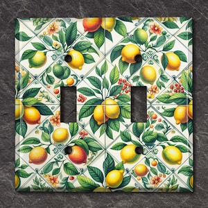 May include: A white light switch cover with a repeating pattern of lemons, limes, and green leaves on a white background.
