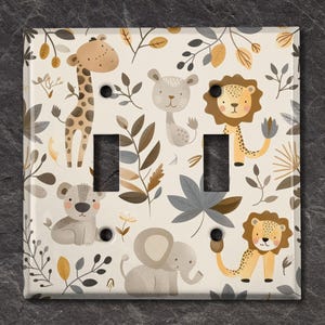 May include: A light switch cover with a white background and a pattern of brown, grey, and yellow animals and leaves. The animals include a giraffe, a lion, an elephant, and a monkey. The leaves are in a variety of shapes and sizes.