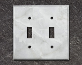 May include: White marble double light switch cover plate with two toggle switches and two screw holes.
