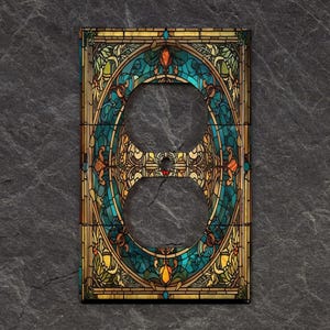 May include: A decorative outlet cover with a stained glass design featuring a blue, green, and gold color scheme. The design is reminiscent of a stained glass window with intricate floral patterns.