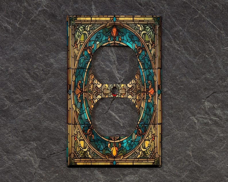 May include: A decorative outlet cover with a stained glass design featuring a blue, green, and gold color scheme. The design is reminiscent of a stained glass window with intricate floral patterns.