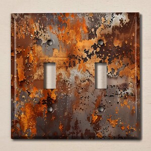 May include: A double light switch cover featuring a rusty metal design. The cover has a mottled brown, orange, and grey colour scheme.