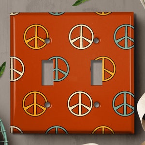 May include: A light switch cover with a repeating pattern of peace signs in orange, yellow, blue, and green on a rust-colored background.