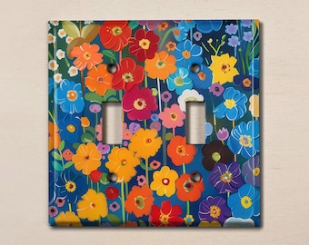 Könnte beinhalten: Ein Lichtschalter-Abdeckung mit einem bunten Blumenmuster. Das Design zeigt eine Vielzahl von Blumen in Rot-, Orange-, Gelb-, Blau- und Lilatönen auf einem dunkelblauen Hintergrund.