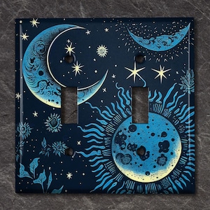 May include: A light switch cover with a celestial design featuring two moons, stars, and a sun with a blue and yellow color scheme.