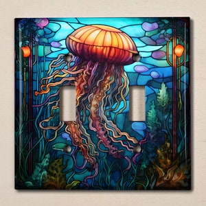 May include: A decorative light switch cover featuring a stained-glass design of a jellyfish. The jellyfish is orange and purple, with long tentacles. The background is blue and green, with aquatic plants and other sea life.