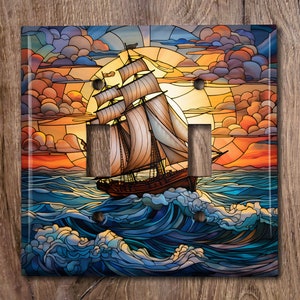 May include: A stained glass light switch cover depicting a ship sailing on a blue sea with a sunset in the background.