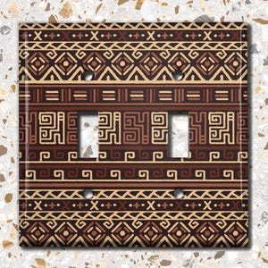 May include: A brown and beige light switch cover with a geometric pattern. The pattern is made up of lines, squares, and diamonds.
