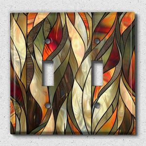 May include: A decorative light switch cover featuring a stained glass design with abstract shapes in shades of orange, brown, and green.
