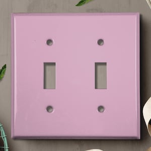 May include: A light pink double light switch plate with two toggle switches and two screw holes.