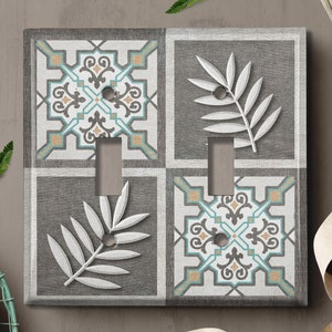 May include: A light switch cover with a decorative design featuring a gray background with white leaf patterns and blue and brown geometric tile patterns.