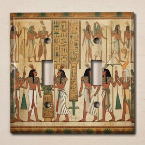 May include: A light switch cover featuring a vintage illustration of Egyptian hieroglyphics and figures in a procession. The figures are depicted in a muted color palette of browns, yellows, and greens.