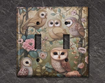 May include: A decorative light switch cover featuring a whimsical design of owls perched on branches amidst flowers. The artwork showcases a soft color palette of beige, brown, and pink, creating a vintage aesthetic. The cover has two switch openings and two screw holes.