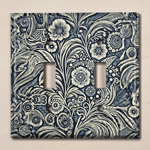 May include: A light switch cover with a decorative floral pattern in shades of blue and white. The pattern features intricate swirls and leaves.