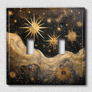 May include: A light switch cover with a black background and gold stars and swirls. The switch cover is designed to look like a night sky.