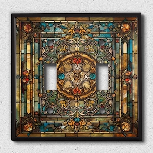 May include: A double light switch cover featuring a stained glass design. The design includes a circular pattern of blue, green, yellow, and red glass pieces, surrounded by a border of floral motifs.