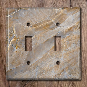 May include: A double light switch cover with a light brown and gray marble pattern.