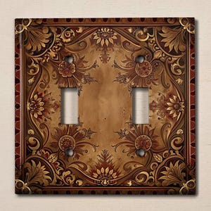 May include: A decorative light switch cover with a brown and gold floral design. The cover has a red border and a distressed look.