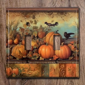 May include: A double light switch cover featuring a vintage illustration of pumpkins, leaves, and birds in autumnal colors. The background is a muted yellow with a brown border.