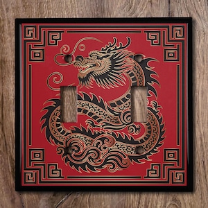 May include: A black and gold dragon design on a red background with a black frame. The design is a traditional Chinese dragon with swirling clouds and a geometric border. The switch plate is for a double light switch.