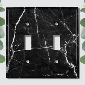 May include: Black and white marble light switch cover with two toggle switches.