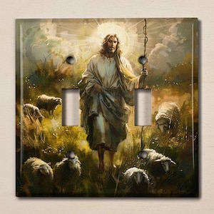 May include: A light switch cover featuring a painting of Jesus Christ as a shepherd, surrounded by sheep in a field. The painting is in a realistic style with warm colors and a soft, ethereal glow.