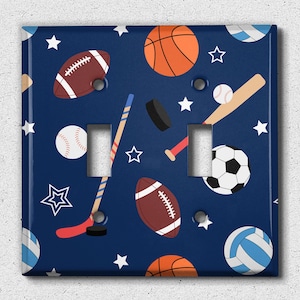 May include: A blue light switch cover with a pattern of sports equipment, including baseballs, basketballs, footballs, hockey sticks, and soccer balls. The background is a dark blue with white stars.