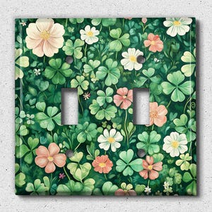 May include: A green light switch cover with a floral pattern of pink and white flowers and green leaves.